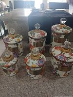 Full set of six floral ceramic canisters with lids displayed on countertop