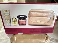 Back of retail box showing cosmetic pouch, full-size perfume, mini spray, body lotion, plus actual pouch in foreground