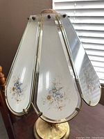 Full view of lamp showing glass shade panels, floral design, and brass base