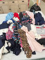 Pile of assorted women’s clothing items showing various colors, patterns and attached tags