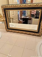 Front view of rectangular gold and black framed mirror on counter