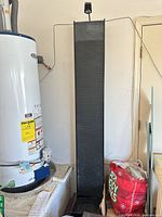 Full view of tall black ribbed fountain with base and pump wires