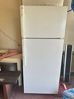 Front view of closed white GE top-freezer refrigerator