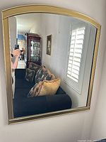 Front view of one gold arched wall mirror mounted on wall
