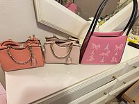 All three handbags side by side on dresser top
