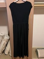 Full view of black calf-length dress on hanger