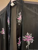 Close-up of satin trim with pink floral embroidery on black cover-up
