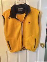 Front view of yellow Champion fleece vest on hanger