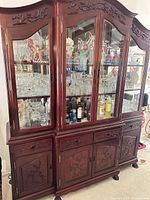 Full front view of dark wood china cabinet with glass doors, drawers and carved details