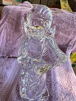 Front view of clear crystal angel figurine showing facial features, wings, and book detail