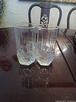 Two matching clear cut-glass tumblers on table
