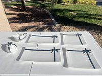 Full set: four plates, sugar bowl, creamer displayed outdoors