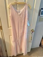 Full view of pink sleeveless beaded evening gown hanging on door