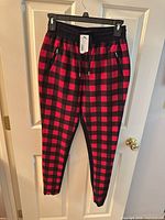 Full view of red/black flannel pants hanging, showing overall style and condition
