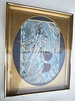Front view of framed print showing gold frame and oval mat
