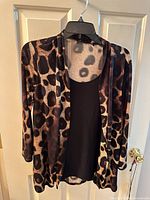 Front view of leopard print jacket over black tunic on hanger