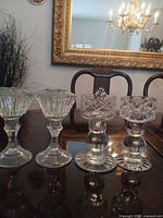 All four crystal candlesticks grouped on table showing differing styles