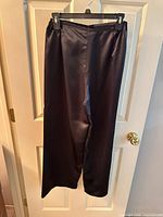 Full view of black polyester pants hanging on hanger