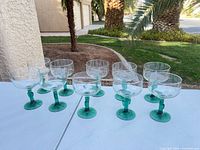 Full set of 10 green-stem cocktail glasses on table