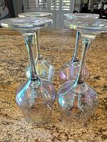 Four upturned iridescent wine glasses showing stems and bowls