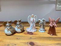 All five angel figurines lined up on tabletop