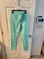 Full view of teal jeans hanging, showing overall style and color