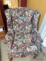 Front view of floral wingback armchair showing upholstery, arms, cushion and legs