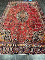 Full view of entire red Mashhad rug showing overall pattern and wear