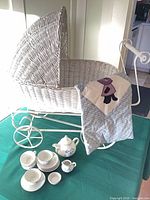 overall view of wicker pram, quilt draped, complete tea set displayed