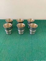 Six pewter shot glasses upright showing shape and finish
