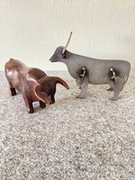 Hardwood and steel bull figures side by side on surface