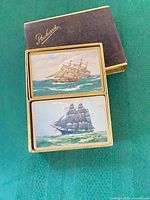 Open velveteen Packard case showing two sailing ship decks