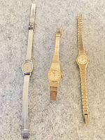 Three wristwatches side by side showing dials and bracelets