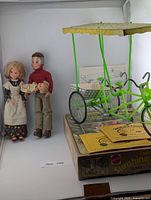 Family dolls beside boxed Surrey Cycle