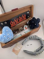 Box open showing assorted jewelry, plush charms, headband