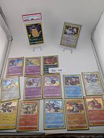 Group shot showing PSA-graded Pikachu on stand, Lugia on stand, and fourteen additional Celebrations holo cards