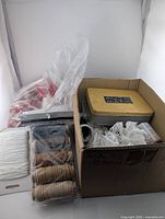 Overall view of box contents including cord spool, wooden discs, lace, metal tin