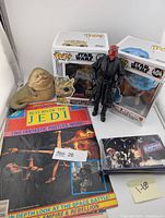 Group shot of Funko Pops, Darth Maul figure, Jabba figurine, magazine and trading cards