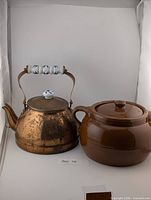 Front view of copper kettle and stoneware crock side by side