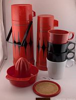 Group shot of both thermoses, stackable mugs, juicer, coaster