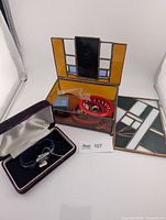 Lot overview showing stained glass jewelry box open, Birks watch box with blue-strap watch, separate stained glass panel