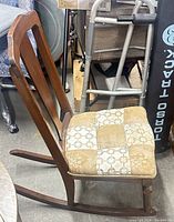 Side view of wooden armless rocking chair showing frame, runners, and patchwork cushion