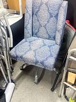 Front view of blue paisley upholstered wingback chair on casters