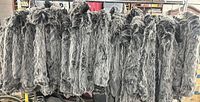 Rack holding multiple identical black faux fur jackets