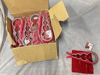 Cardboard box containing multiple red silicone jar openers, one opener and grip pad displayed outside the box
