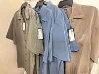 Front view of several shirts on hangers displaying colors and tags attached