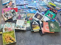 Wide view of heap of assorted LPs spread on floor, showing variety of titles and cover art
