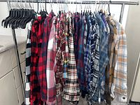Rack holding 28 assorted men’s plaid flannel shirts in various colors and patterns