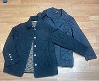 Two black quilted jackets laid flat showing fronts