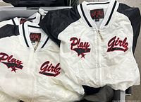 Close-up of white jacket front showing embroidery, zipper and neck label